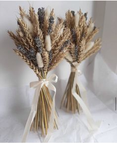 two vases filled with dried flowers on top of a table