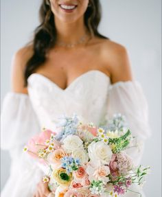 a woman in a wedding dress holding a bridal bouquet with white and pink flowers