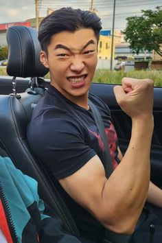 a man sitting in the back seat of a car with his arm up and fist raised