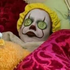 a creepy clown laying in bed with stuffed animals