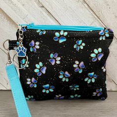 a black and blue dog paw print zippered pouch with a turquoise keychain