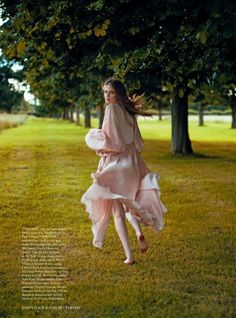 a woman in a pink dress is walking through the grass