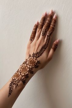 a woman's hand with hennap and flowers on her left arm, against a white wall