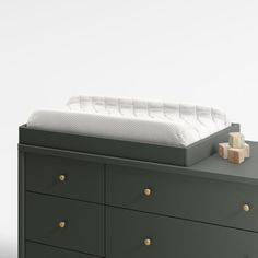 a green dresser with drawers and a white mattress on it's top, in front of a white wall