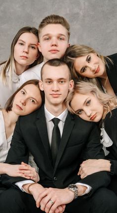 a group of young people posing for a photo in front of a gray background with their arms around each other