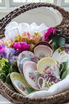 a wicker basket filled with china and flowers