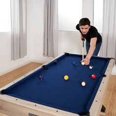 a woman is playing pool on a blue billiards table in the living room