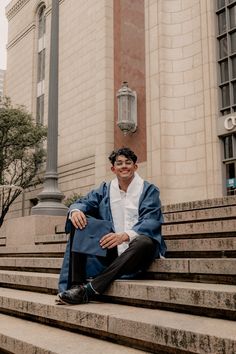 a man sitting on the steps in front of a building wearing a blue jacket and white shirt