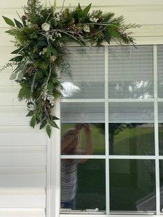 a person taking a photo of a wreath on the window sill