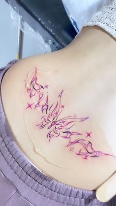 a woman's lower back tattoo with pink flowers and stars on the side,