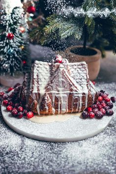 a cake with icing and cranberries on a plate next to a christmas tree