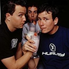 three young men are posing for the camera with drinks in their hands and one is sticking his tongue out