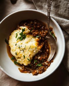 a white bowl filled with mashed potatoes and lentils on top of a table