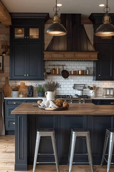 a kitchen with two stools in front of the island and three lights above it