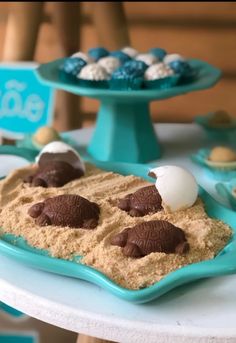 desserts are displayed on blue trays with white frosting and chocolate covered cookies