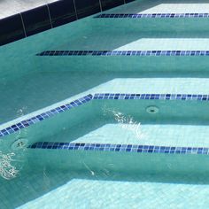 an empty swimming pool with blue tiles on the side and water running down it's sides