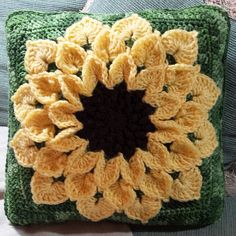 a crocheted pillow with a yellow flower on the front and black center in the middle