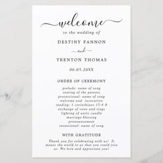 the wedding ceremony program is displayed on a marble table with white and black text, which reads