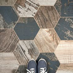 a pair of shoes sitting on top of a wooden floor next to a tiled wall