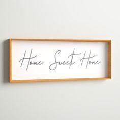 there is a sign that says home sweet home hanging on the wall in front of a white wall