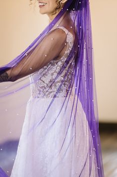 a woman in a white dress and purple veil