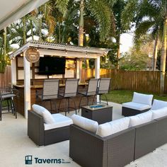 an outdoor living area with couches, tables and bar in the back yard on a sunny day