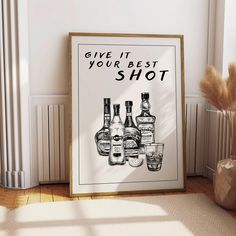 a framed poster that says give it your best shot with liquor bottles on the floor