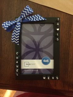 a black frame with a blue and white bow on it sitting on a wooden table