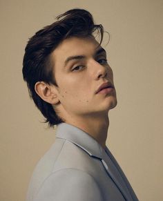 a young man in a suit poses for the camera with his head tilted to the side