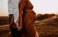 a man and woman holding hands while standing next to each other in an open field