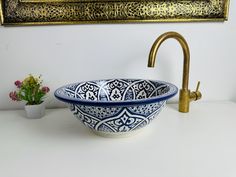 a blue and white bowl sitting on top of a counter next to a faucet