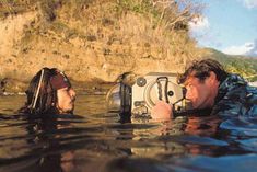 a man and woman in the water with a camera on their head looking at each other