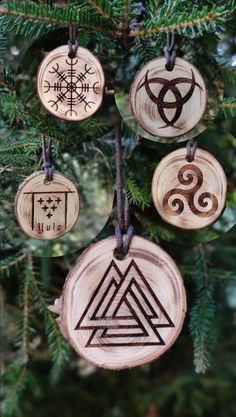 four wooden ornaments hanging from a christmas tree in the shape of celtic symbols and triskes