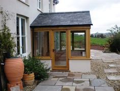 a small white house with a wooden door and glass windows on the side of it