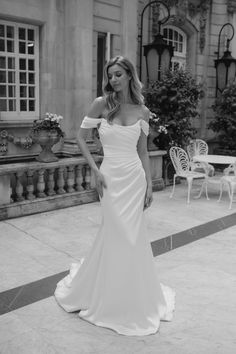 a woman in a white wedding dress standing on a patio with her hand on her hip