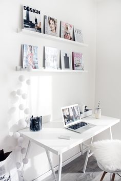 a white desk and chair in a room with pictures on the wall above it,