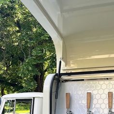 the back end of a white truck with three wooden spoons in it