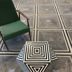 a green chair sitting next to a black and white table on top of a tiled floor