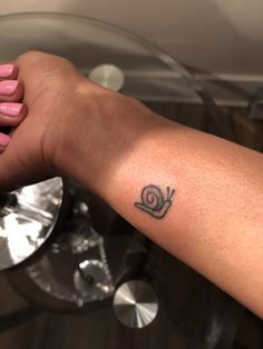 a woman's arm with a small snail tattoo on it