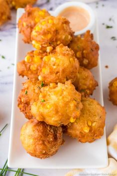 some fried food on a white plate with dipping sauce