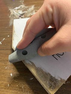 a person is using a small piece of paper to cut something