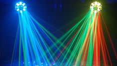 three colorful lights are shining brightly in the dark room with people sitting on the floor