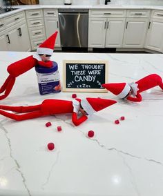 two elfs are sitting on the kitchen counter with candy in front of them and one is holding a sign that says we thought there were some candy