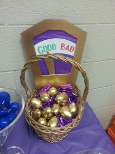 a basket filled with gold eggs sitting on top of a table next to some candy