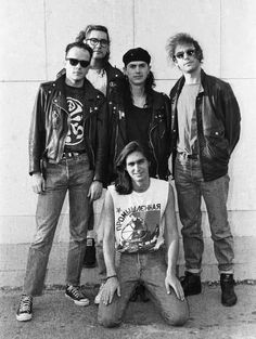 an old black and white photo of four men in leather jackets, one with sunglasses on his head