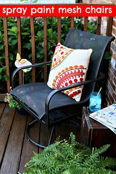 a black chair sitting on top of a wooden deck next to green plants and flowers