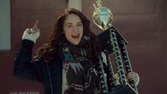 a woman holding up a trophy and giving the peace sign