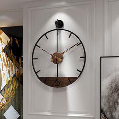 a large clock mounted to the side of a white wall next to a framed photograph