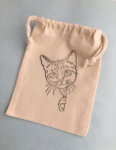 a small drawstring bag with a cat drawn on the front and side of it