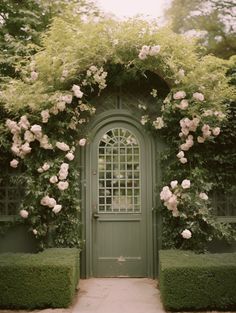 a green door surrounded by hedges and flowers